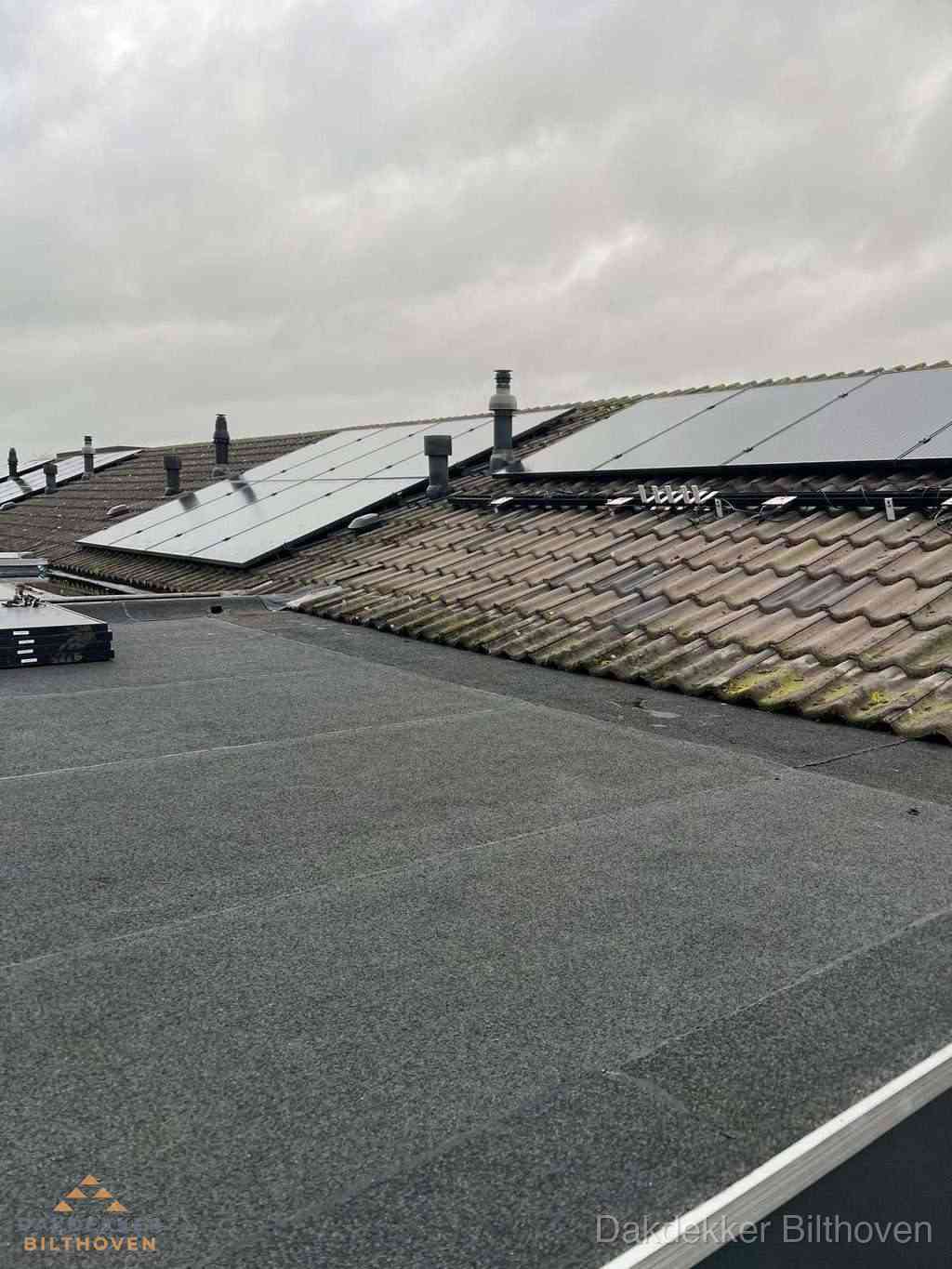 Plat dak inspectie met bitumen bedekking naast schuin pannendak in Bilthoven