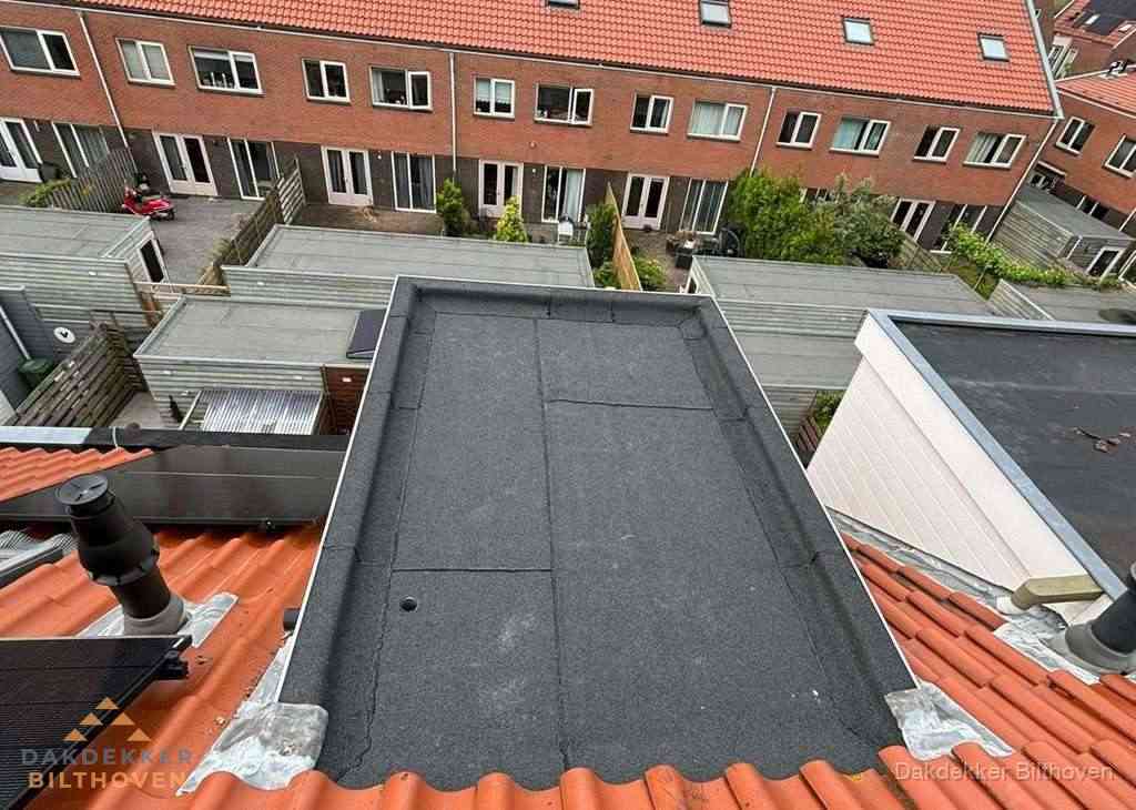 Plat dak met bitumen bedekking naast dakkapel in Bilthoven