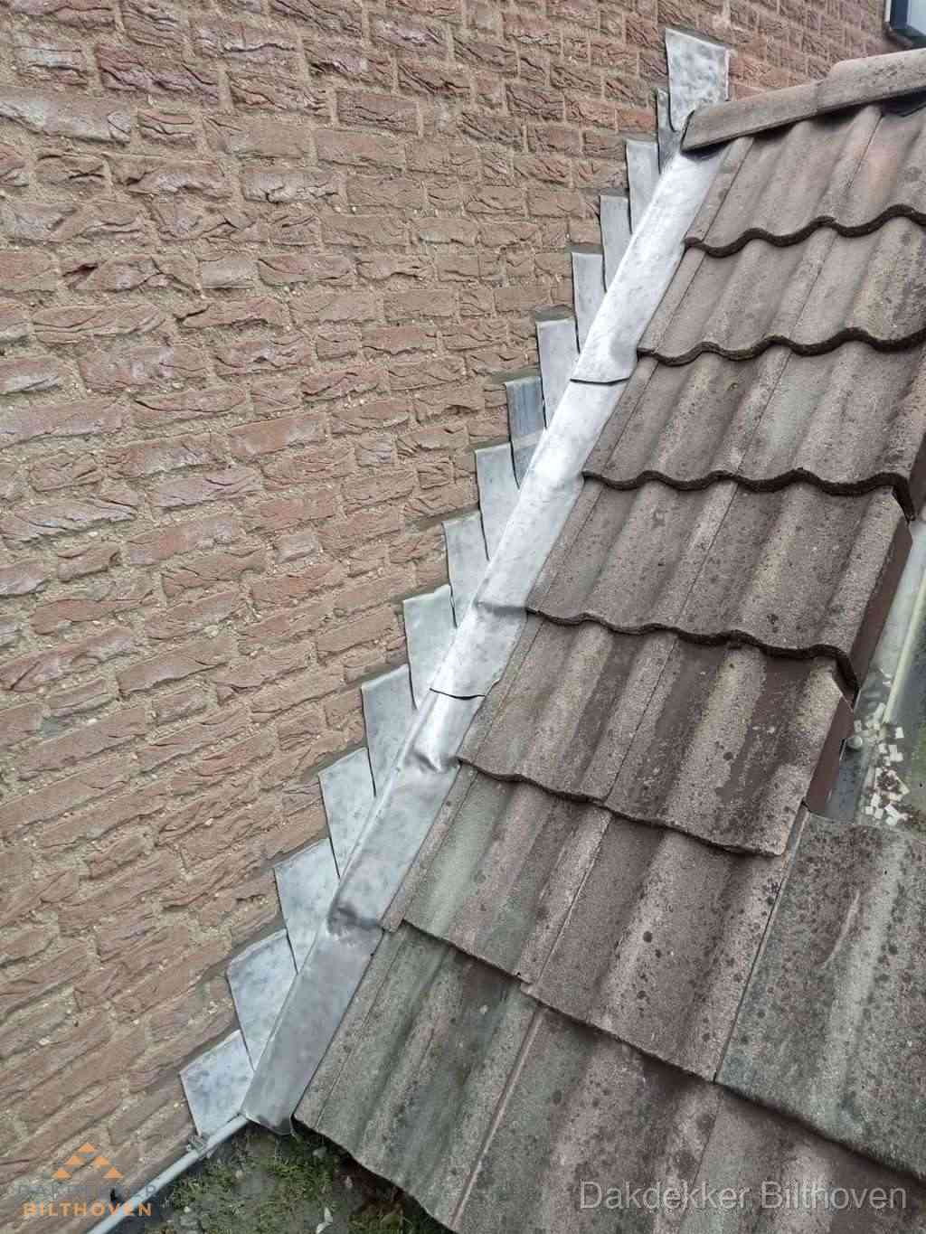 Loodslabben langs dakaansluiting bij bakstenen muur in Bilthoven